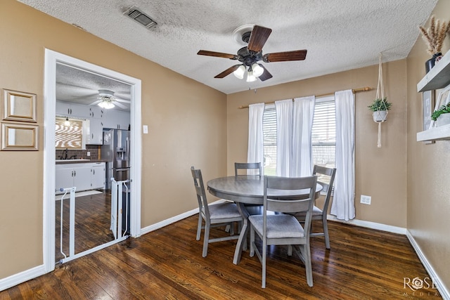 dining room with a textured ceiling, dark wood-type flooring, visible vents, and baseboards