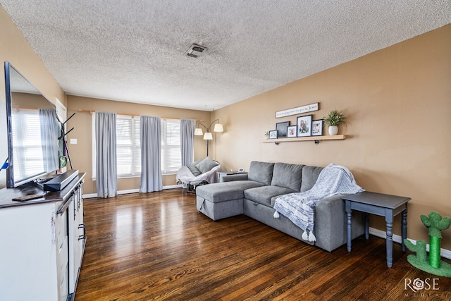 living area with dark wood-style floors, visible vents, a textured ceiling, and baseboards