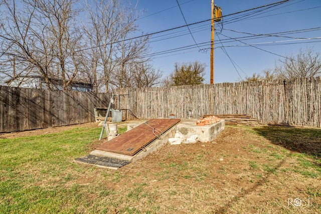 entry to storm shelter featuring a fenced backyard and a yard