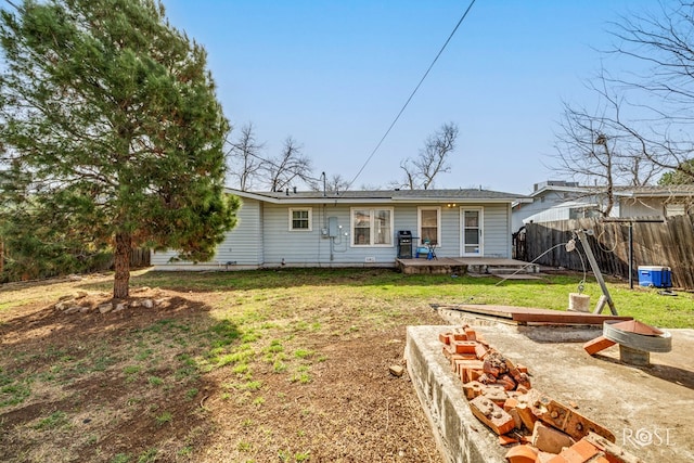 rear view of property featuring a yard and fence