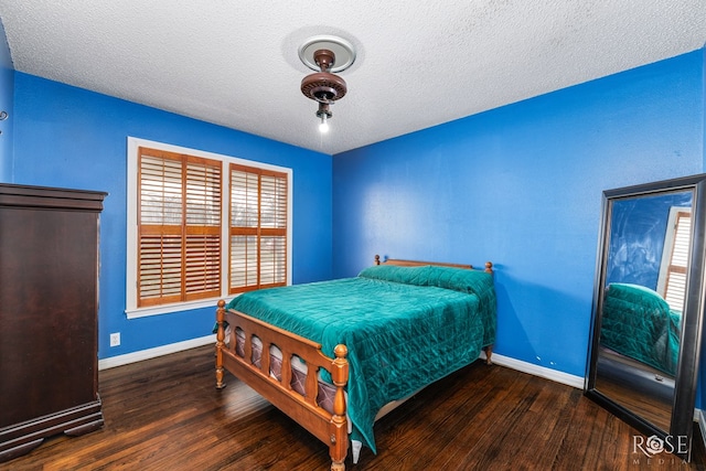 bedroom with a textured ceiling, baseboards, and wood finished floors