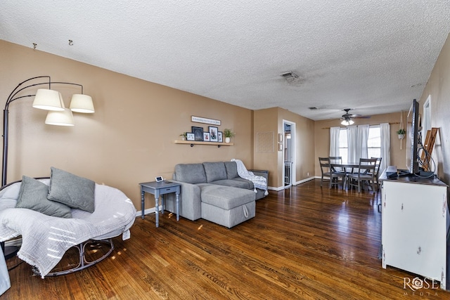 living area featuring baseboards, visible vents, ceiling fan, wood finished floors, and a textured ceiling