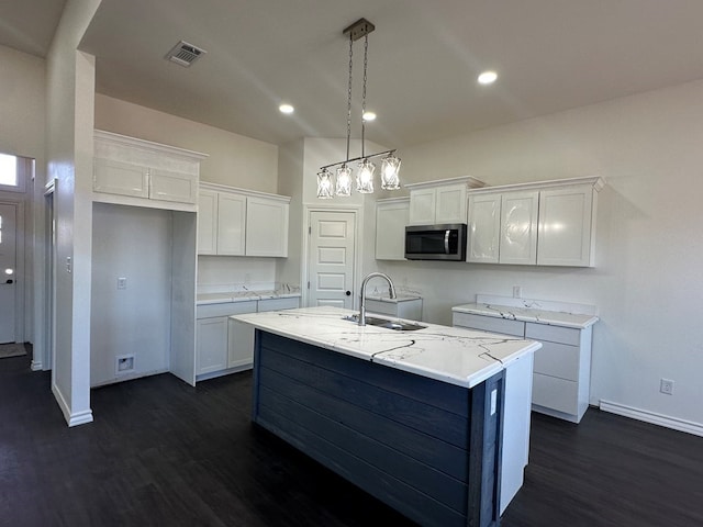 kitchen featuring white cabinetry, sink, a center island with sink, and decorative light fixtures