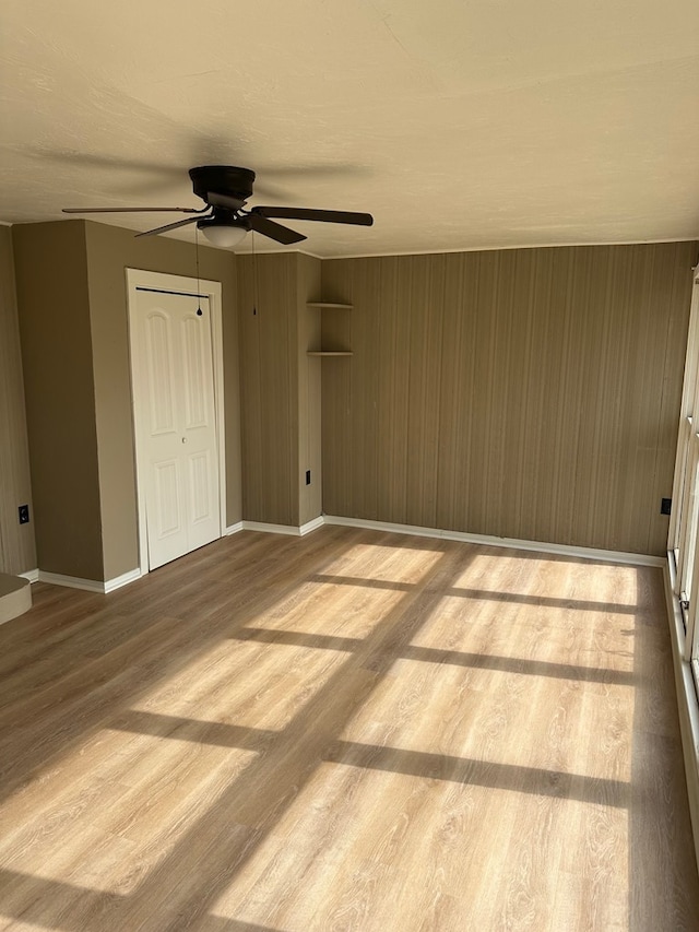 unfurnished bedroom featuring light wood-type flooring, ceiling fan, and a closet