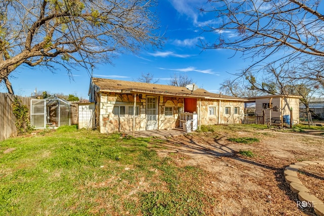 back of house featuring an outdoor structure and a lawn