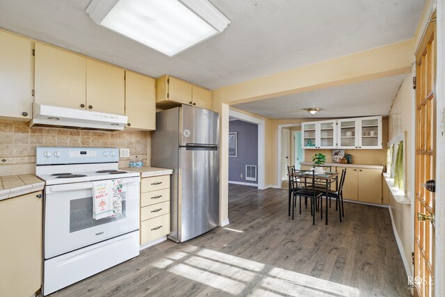 kitchen featuring tasteful backsplash, wood-type flooring, stainless steel fridge, cream cabinets, and electric stove