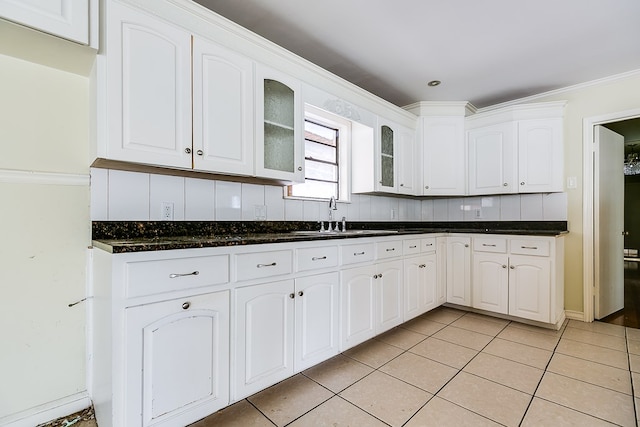 kitchen featuring light tile patterned flooring, a sink, white cabinetry, decorative backsplash, and glass insert cabinets