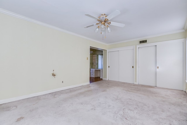 unfurnished bedroom with visible vents, ornamental molding, two closets, and carpet flooring