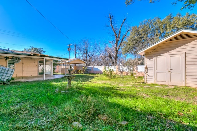 view of yard with a storage shed, a patio area, fence, and an outdoor structure