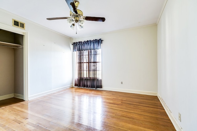 unfurnished bedroom with ornamental molding, wood finished floors, visible vents, and baseboards