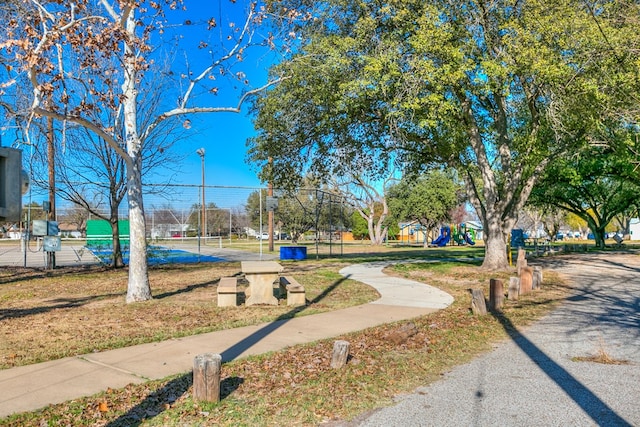 surrounding community with a tennis court and fence