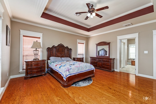 bedroom with crown molding, light hardwood / wood-style floors, and a raised ceiling