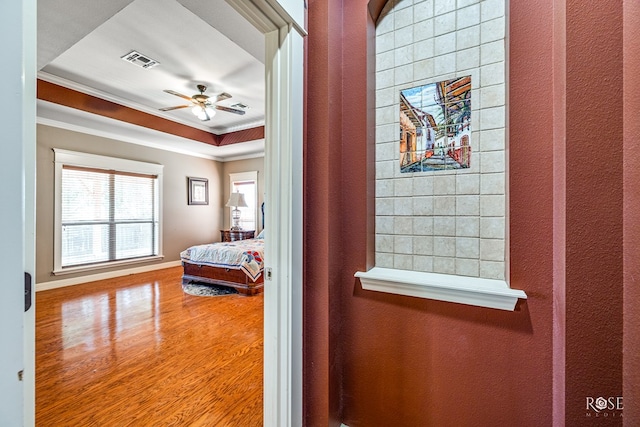 bedroom featuring crown molding, a raised ceiling, and hardwood / wood-style floors