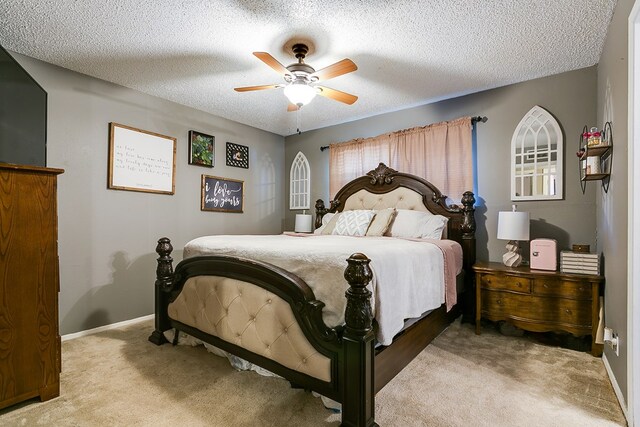 bedroom with ceiling fan, light carpet, and a textured ceiling