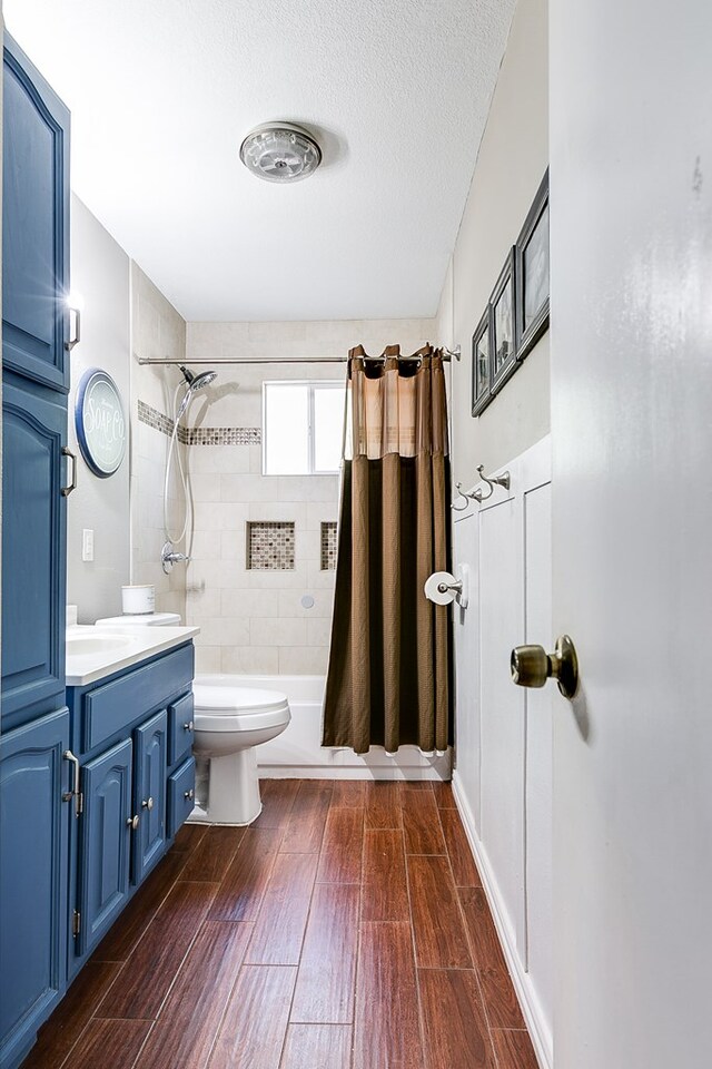 full bathroom with vanity, toilet, a textured ceiling, and shower / bath combo