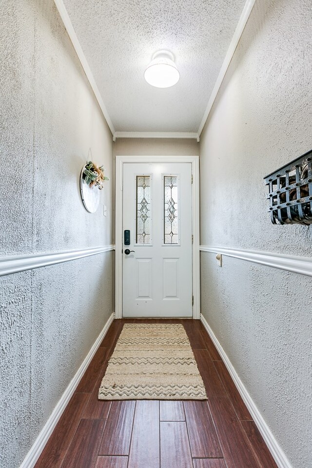 doorway featuring ornamental molding and a textured ceiling