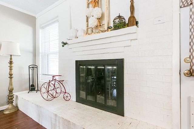 interior details featuring crown molding, wood-type flooring, and a brick fireplace