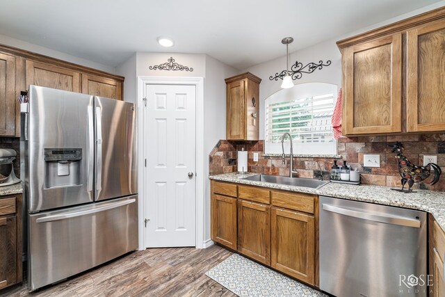 4137 Sedona Trl, San Angelo, TX 76904 - kitchen featuring stainless steel appliances, a sink, brown cabinetry, tasteful backsplash, and wood finished floors
