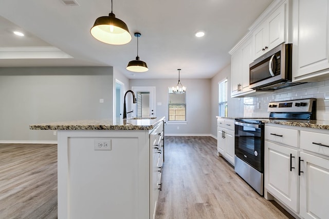 2822 Joshua St, San Angelo, TX 76905 - kitchen featuring appliances with stainless steel finishes, baseboards, light wood-style floors, a center island with sink, and backsplash
