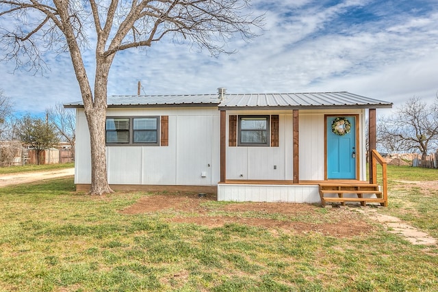 manufactured / mobile home with entry steps, metal roof, and a front lawn