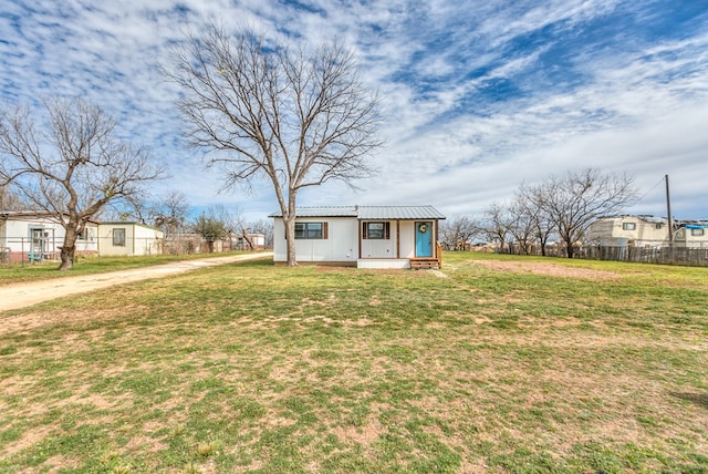 view of front of home with an outbuilding, metal roof, a front lawn, and fence