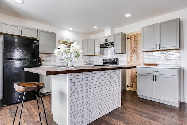 kitchen with butcher block countertops, gray cabinets, freestanding refrigerator, and under cabinet range hood