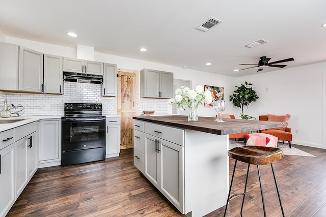 kitchen with visible vents, black range with electric stovetop, gray cabinetry, under cabinet range hood, and wooden counters