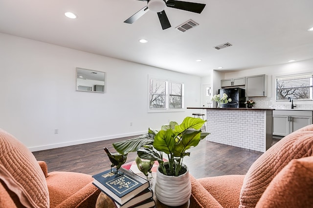 living room featuring dark wood-style floors, baseboards, and visible vents