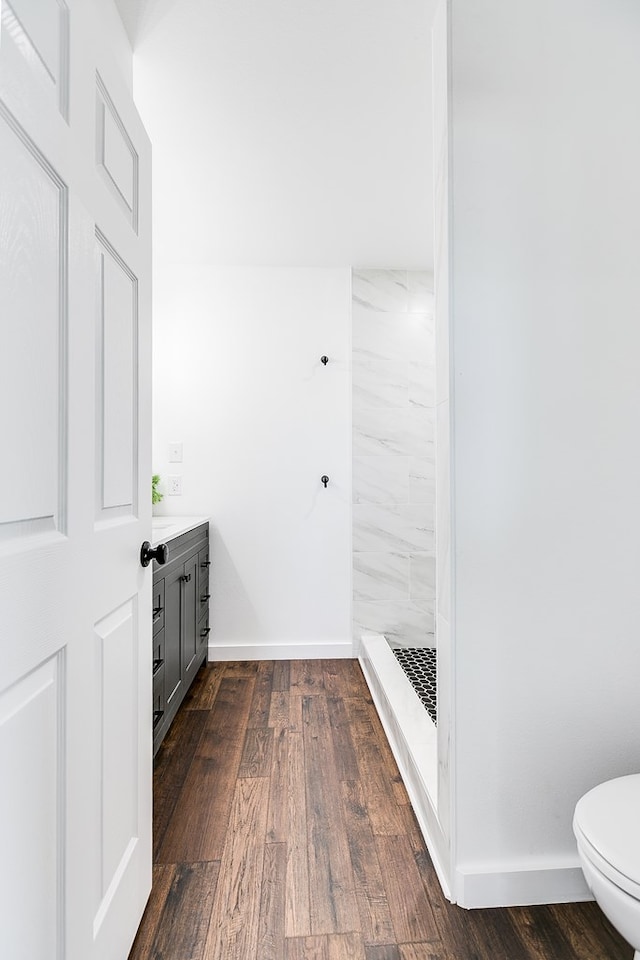 full bath featuring toilet, a shower stall, baseboards, and wood finished floors