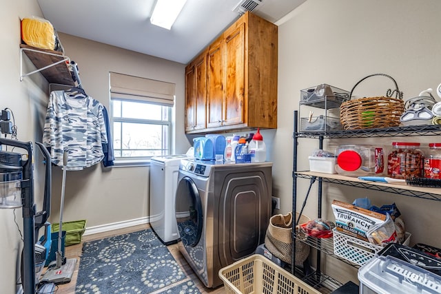 clothes washing area with cabinets and washer and clothes dryer