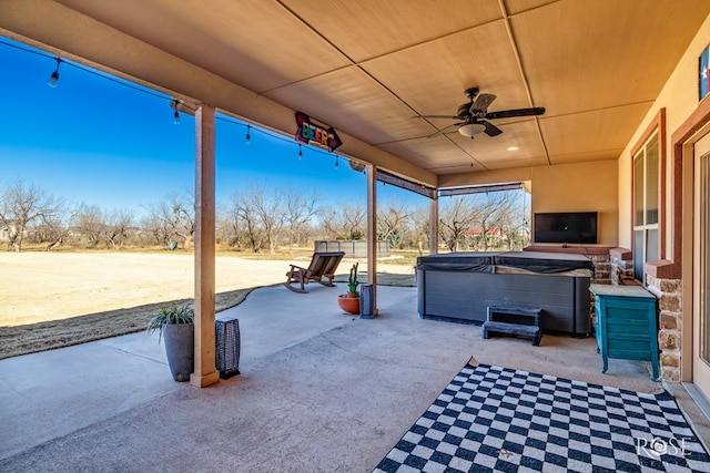 view of patio / terrace with ceiling fan, a fireplace, and a hot tub