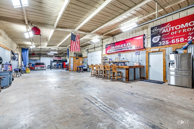 garage featuring stainless steel fridge with ice dispenser and a workshop area