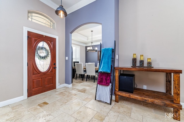 entrance foyer with crown molding, a tray ceiling, and a chandelier