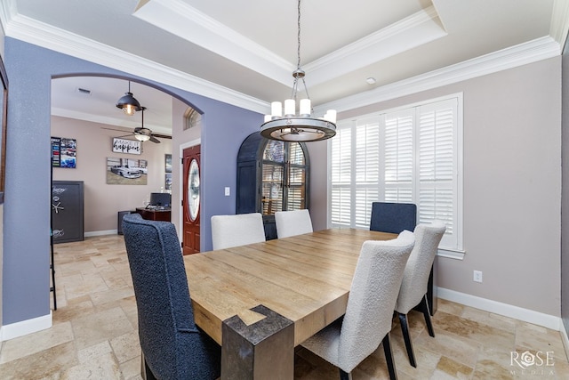 dining space with crown molding, a raised ceiling, and ceiling fan with notable chandelier