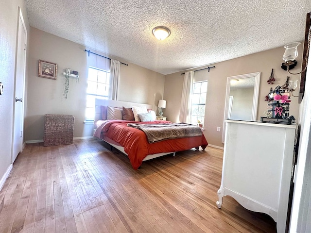 bedroom with multiple windows, hardwood / wood-style flooring, and a textured ceiling