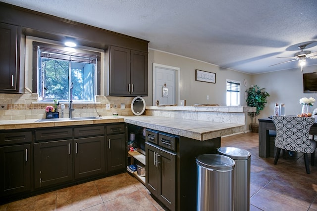 119 Van Zandt St, San Angelo, TX 76905 - kitchen with a peninsula, a textured ceiling, light countertops, backsplash, and light tile patterned floors