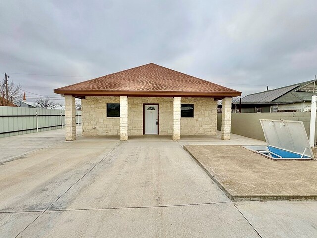 2110 Shelton St, San Angelo, TX 76903 - back of house featuring a patio area, stone siding, and a shingled roof