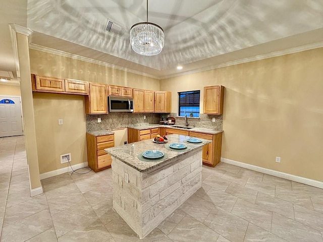 2110 Shelton St, San Angelo, TX 76903 - kitchen with stainless steel microwave, decorative backsplash, a chandelier, ornamental molding, and a center island