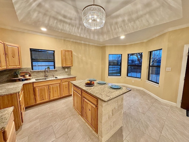 2110 Shelton St, San Angelo, TX 76903 - kitchen featuring ornamental molding, decorative backsplash, a center island, a raised ceiling, and light stone counters