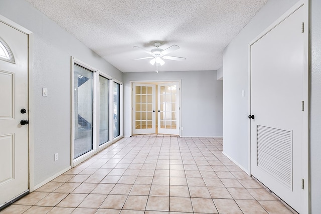 spare room with french doors, light tile patterned floors, visible vents, a ceiling fan, and a textured ceiling