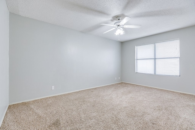 spare room with a textured ceiling, carpet, a ceiling fan, and baseboards