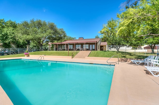 community pool with a yard, a patio, and fence