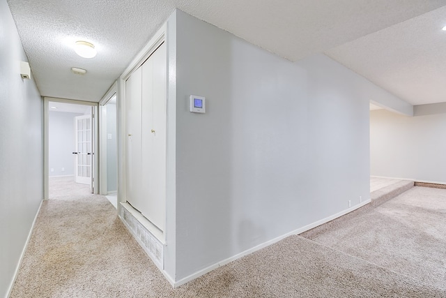 corridor with carpet floors, a textured ceiling, and baseboards