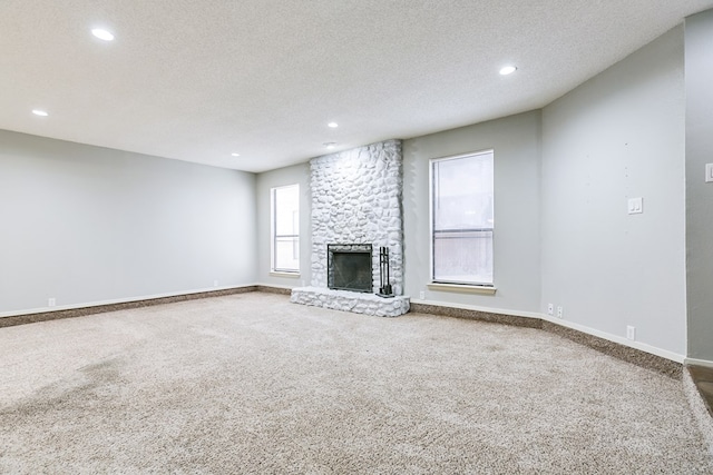 unfurnished living room with a textured ceiling, a fireplace, baseboards, and carpet flooring