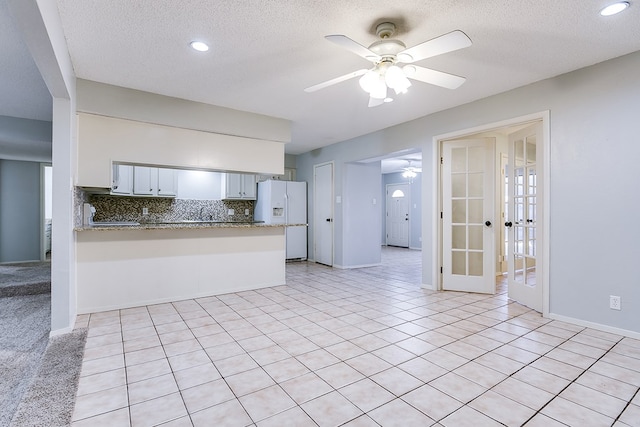 kitchen with white refrigerator with ice dispenser, french doors, backsplash, ceiling fan, and a peninsula