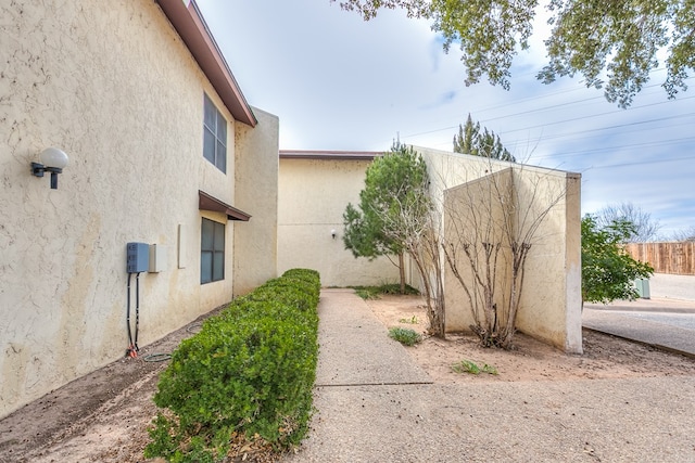 view of side of property with fence and stucco siding