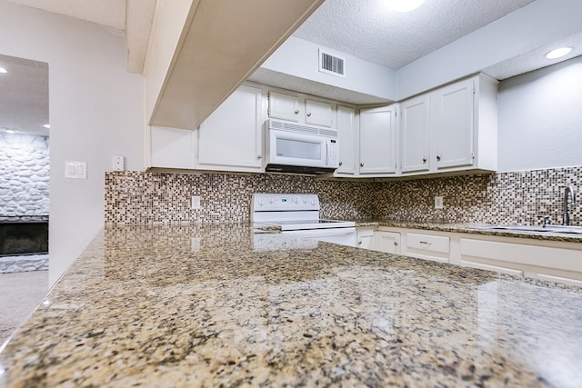 kitchen with white appliances, backsplash, a sink, and visible vents