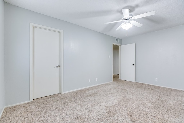 empty room featuring carpet, visible vents, ceiling fan, and a textured ceiling