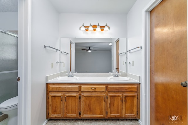bathroom featuring a sink, ceiling fan, toilet, and double vanity