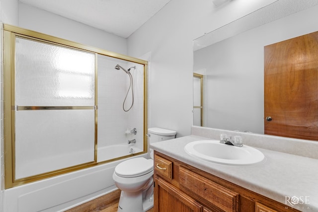 bathroom with vanity, shower / bath combination with glass door, wood finished floors, and toilet
